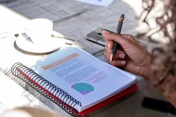 Prise de notes dans un carnet à côté d'une tasse de café